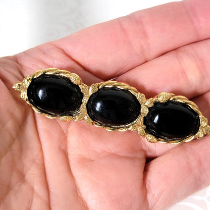 Black and gold vintage bar brooch in hand.