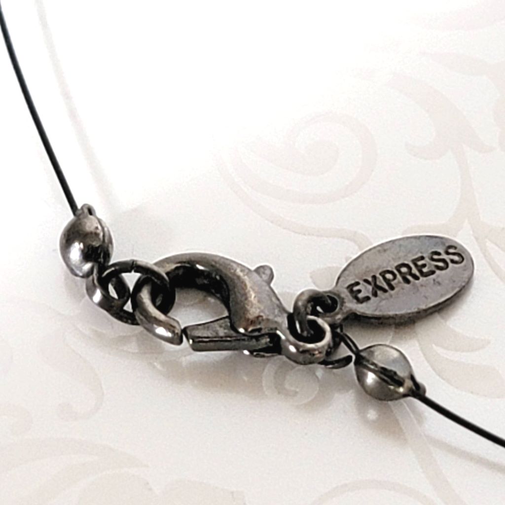 Closeup view of a vintage gunmetal clasp, and Express signature logo tag.