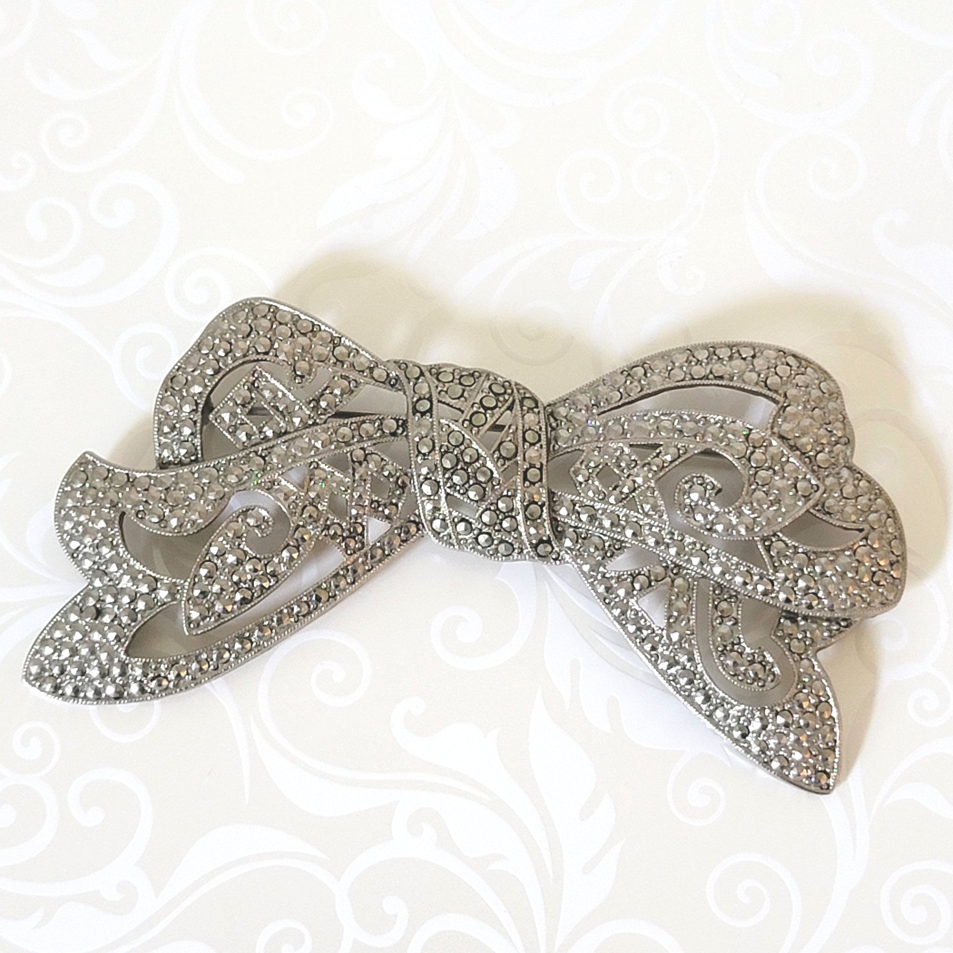 Silver tone bow brooch.
