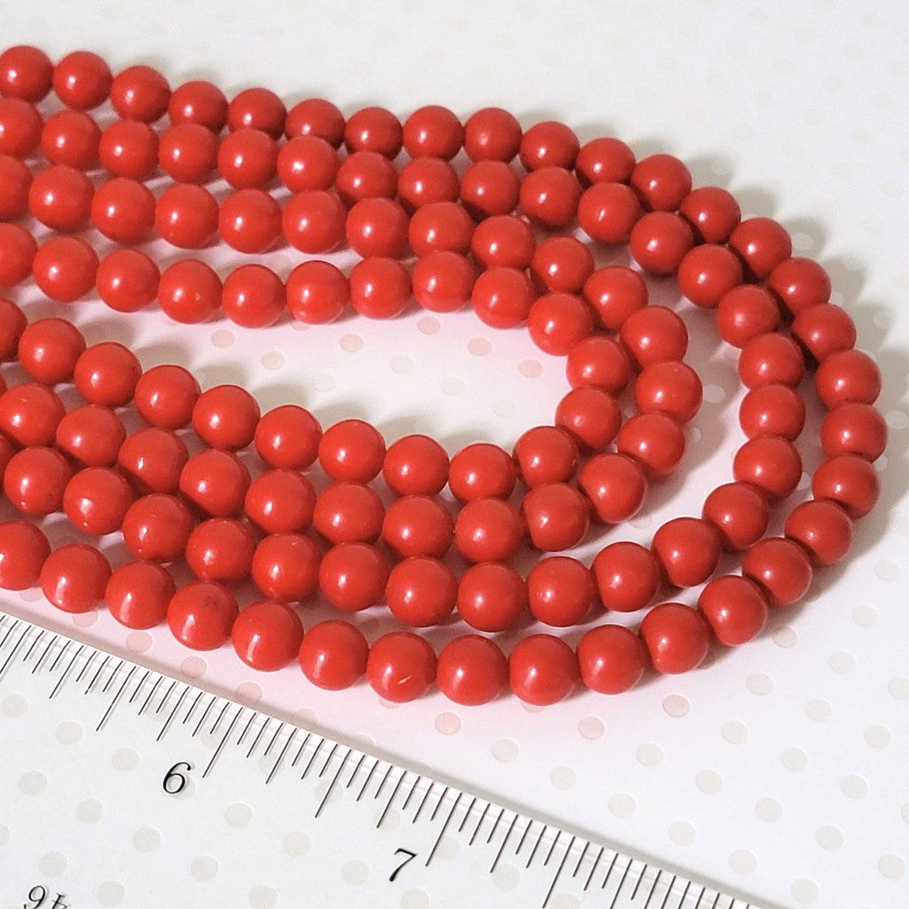 Close-up view of red plastic beads, on a vintage choker.