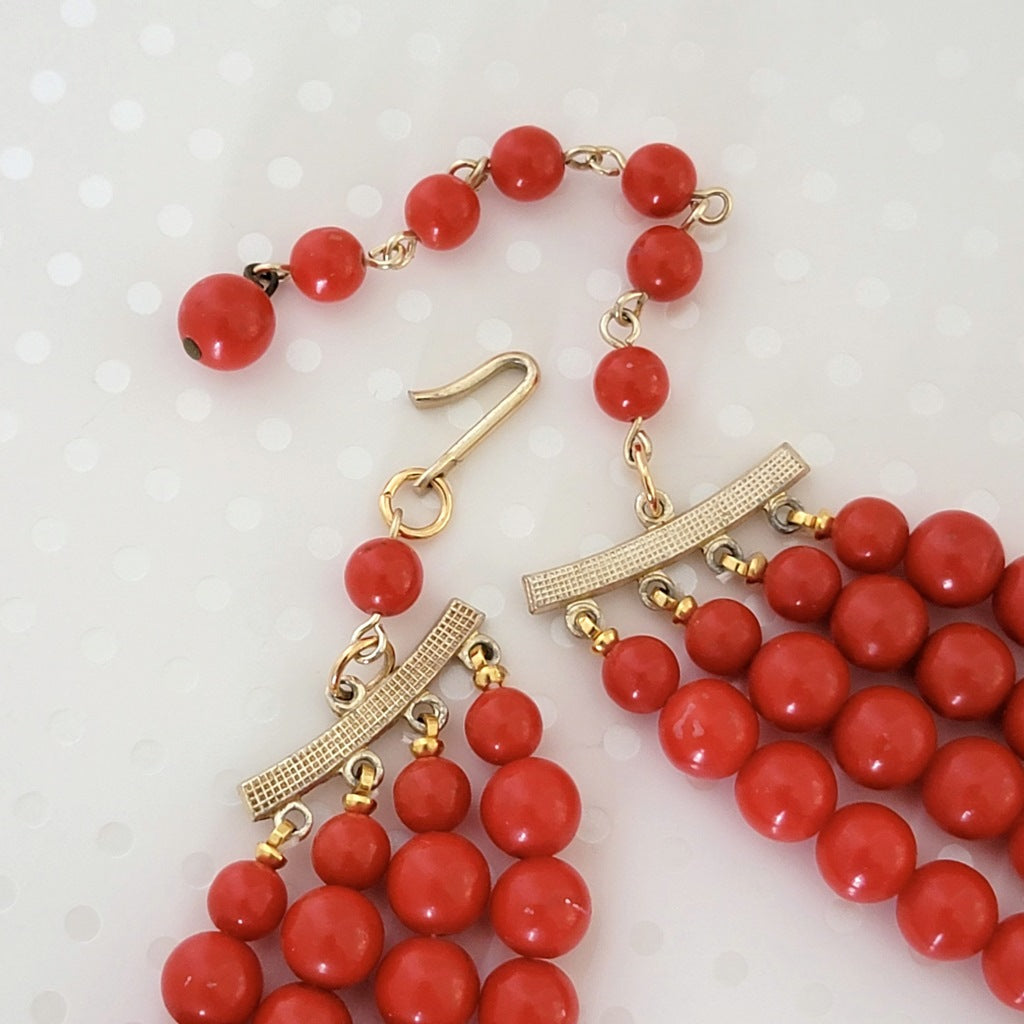 Close-up view of the clasp on a vintage red beaded choker necklace.