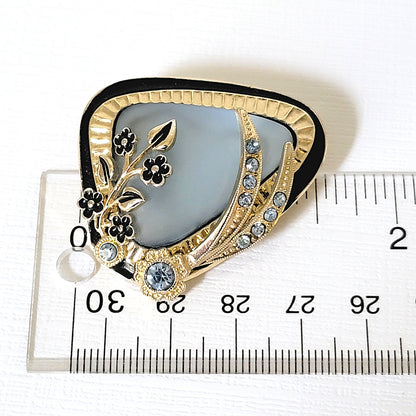 Blue floral pin next to a ruler.