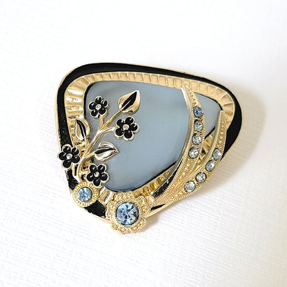 Vintage midcentury style rhinestone brooch with blue frosted glass and black enamel flowers.