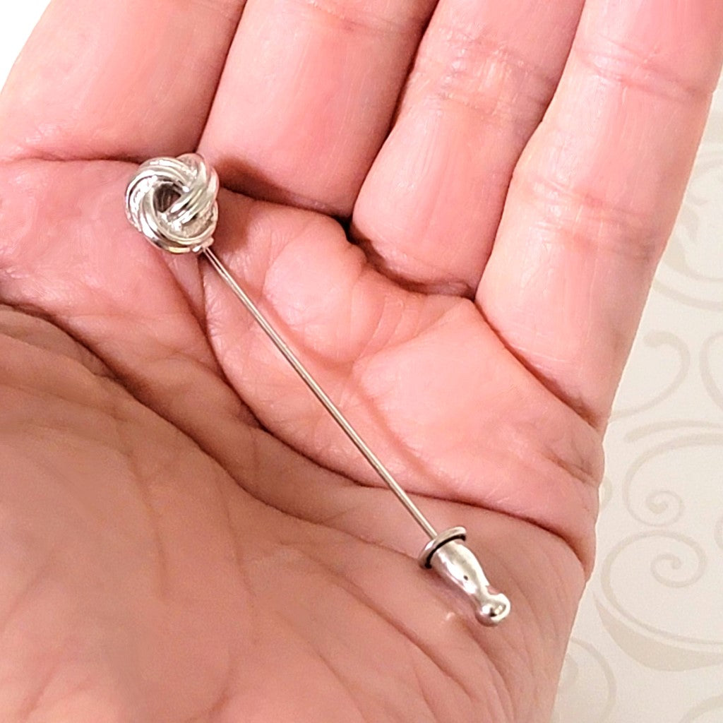 Monet vintage minimalist silver tone knot style stick pin. Shown in hand, for size comparison.