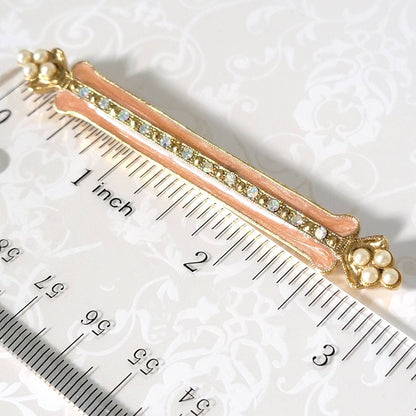 Vintage peach enamel and faux pearl bar brooch, shownn next to a ruler.
