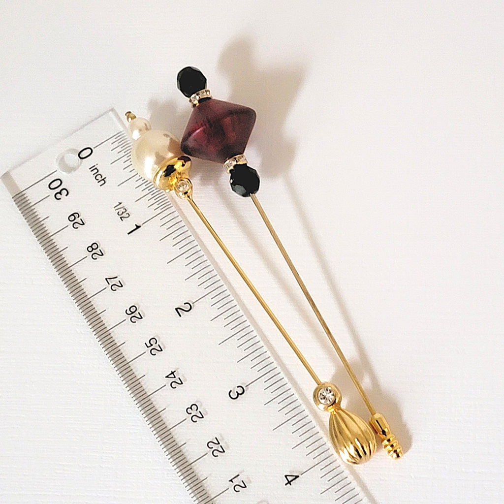 Two stick pins next to a ruler.