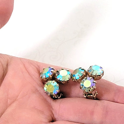 Vintage Weiss triple rhinestone clip-on earrings, with aurora borealis coatings. Shown in hand, for size comparison.