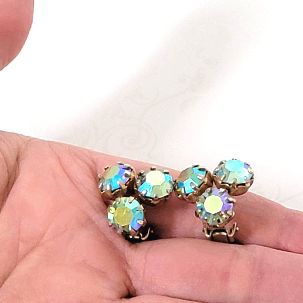 Vintage Weiss triple rhinestone clip-on earrings, with aurora borealis coatings. Shown in hand, for size comparison.