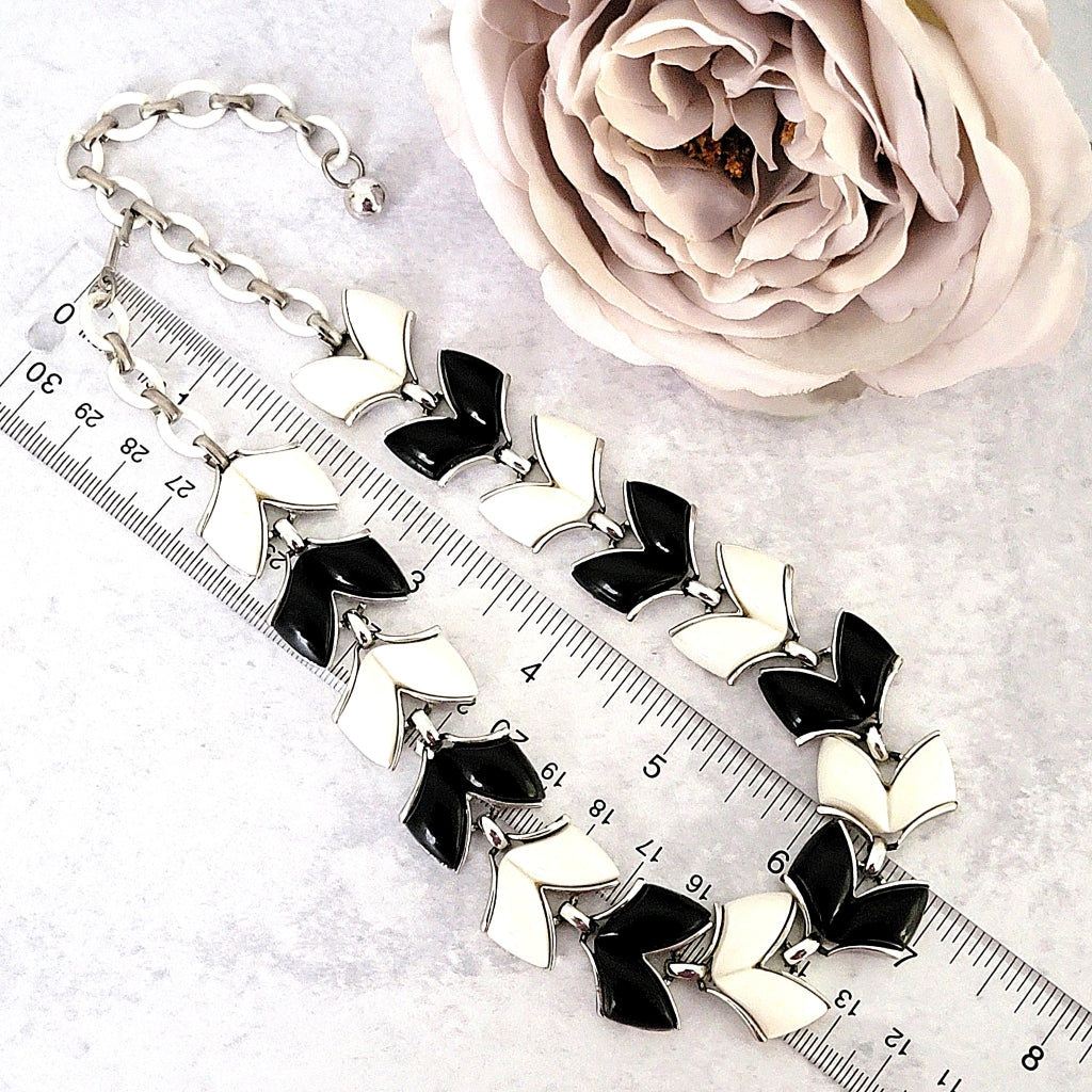 Vintage black and white thermoset necklace next to a ruler.