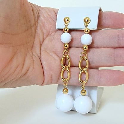 Long white earrings in hand.