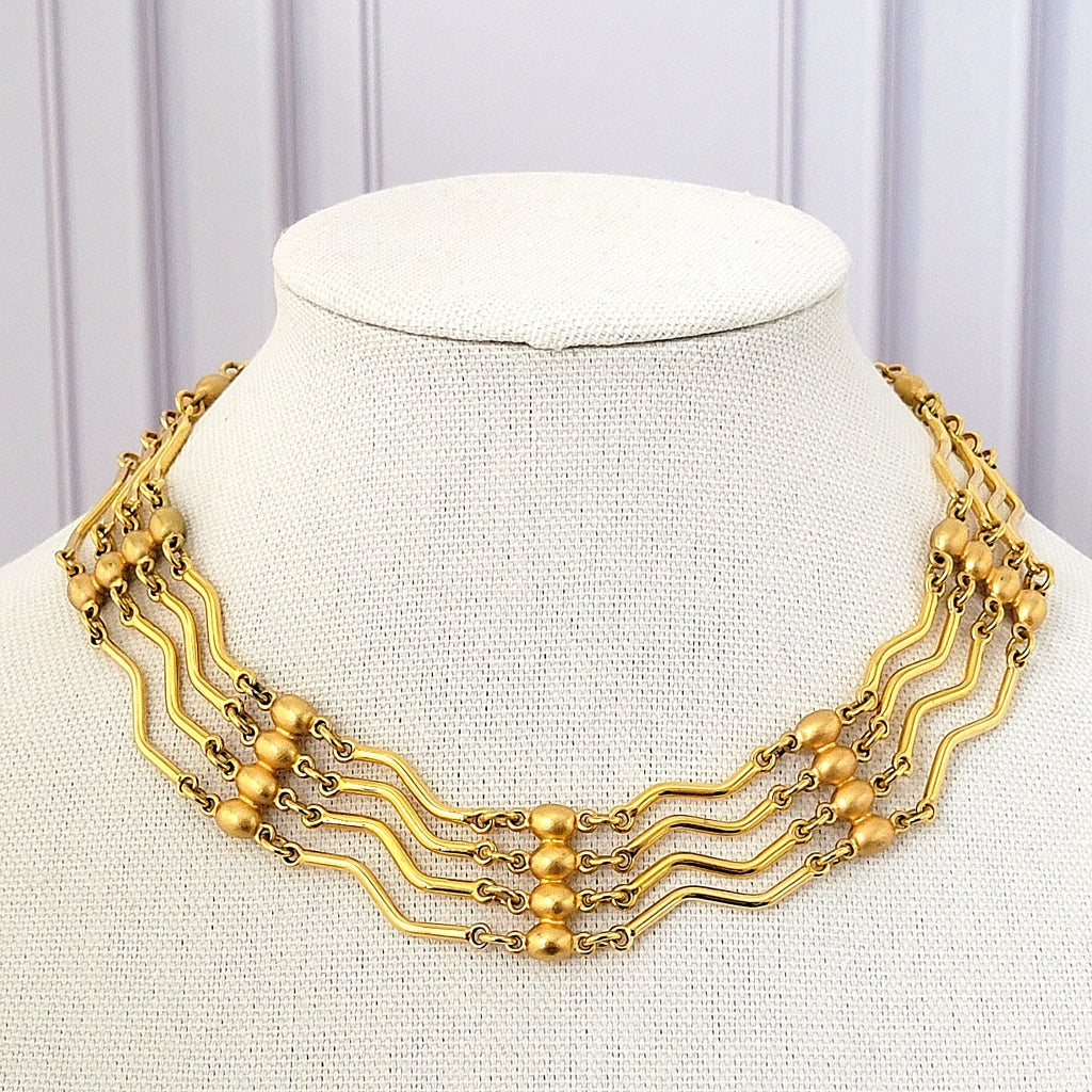 Gold tone choker necklace with wavy bar links.