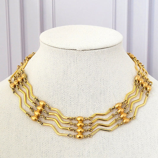 Gold tone choker necklace with wavy bar links.