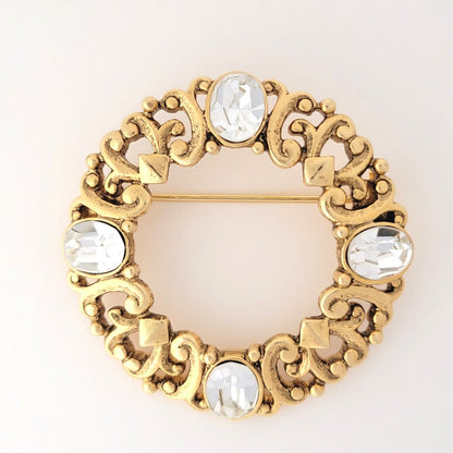 1928 brand rhinestone circle brooch, with gold tone openwork heart scroll design.