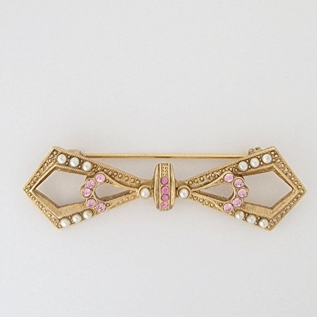 1928 brand gold tone bow brooch with seed pearls and pink rhinestones.
