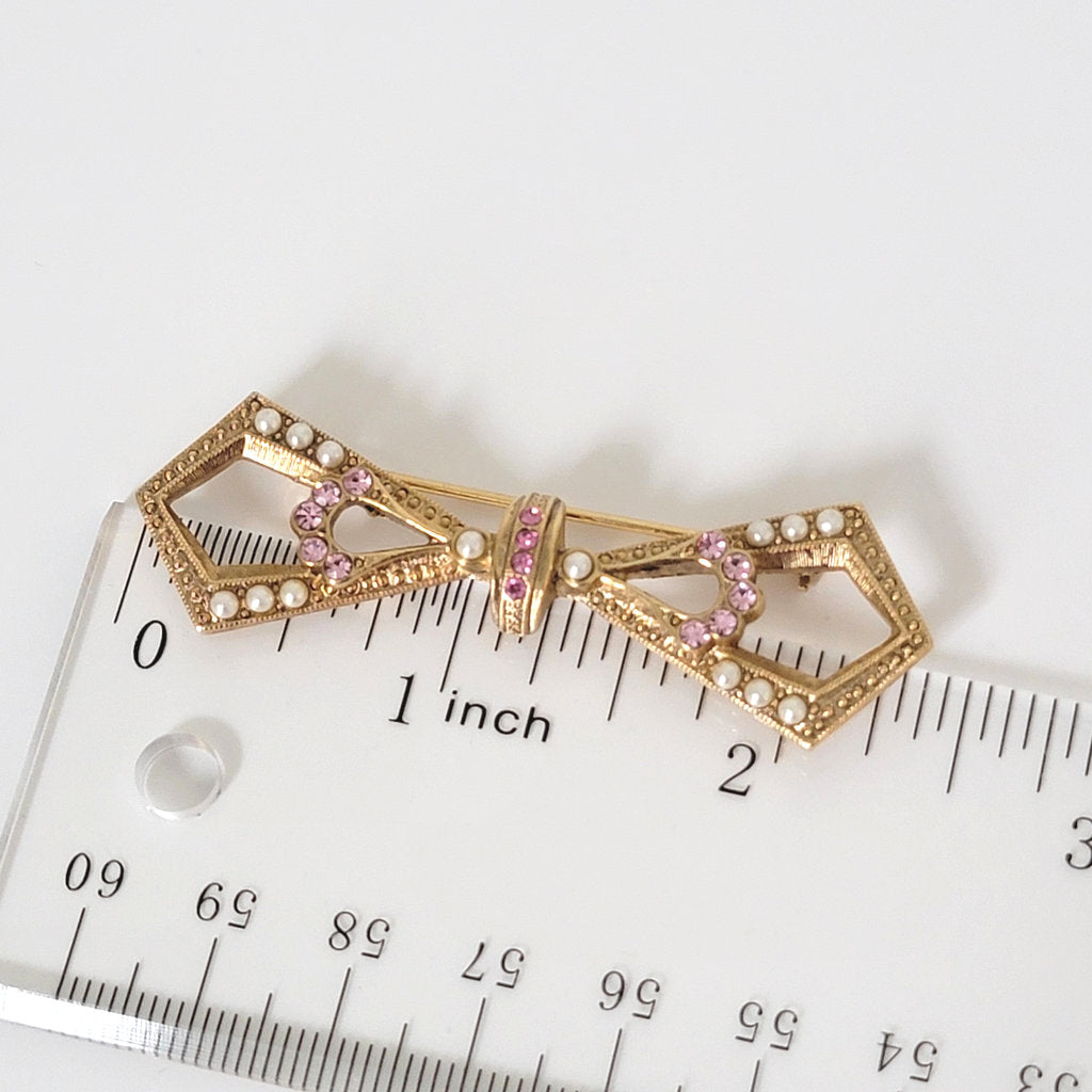 1928 pearl and rhinestone bow brooch next to a ruler.