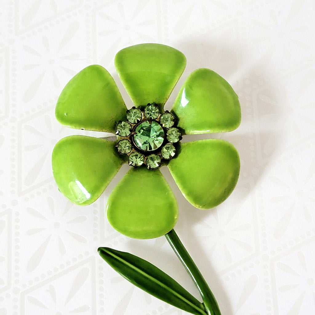 Closeup view of lime green enamel flower pin, with rhinestones.