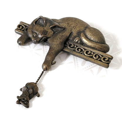 JJ cat brooch, on a ledge, dangling a mouse
