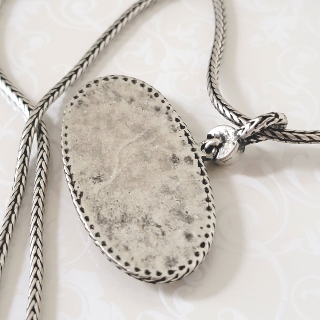 Back closeup view of antiqued silver tone oval pendant and foxtail chain.