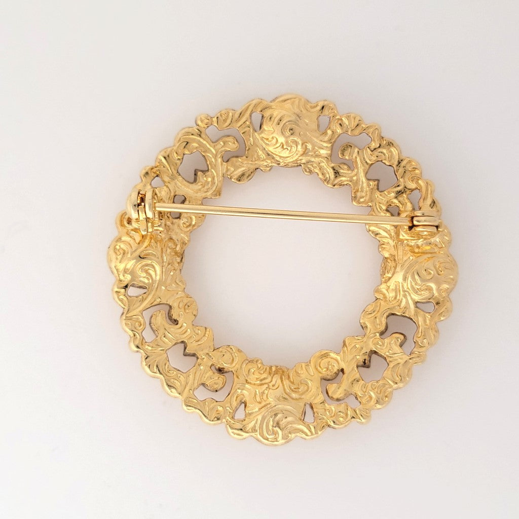 Back view of a 1928 brand circle brooch, with gold tone openwork design.