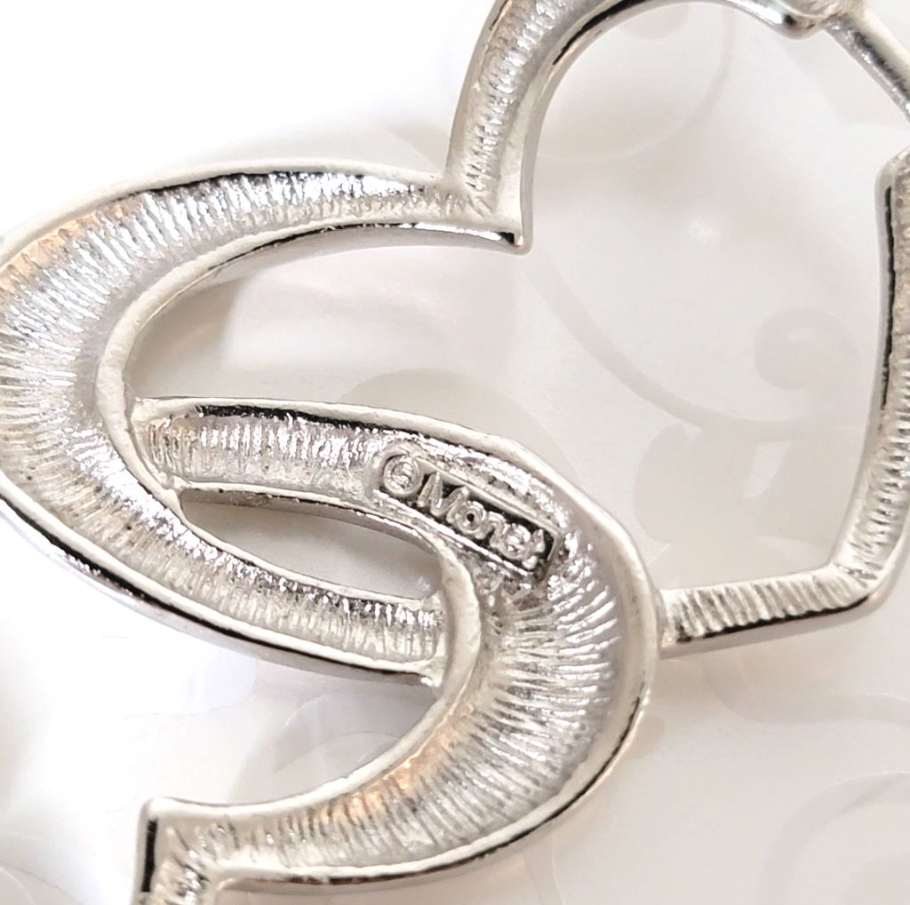 Back view of a Monet silver tone heart bracelet, showing signature logo.
