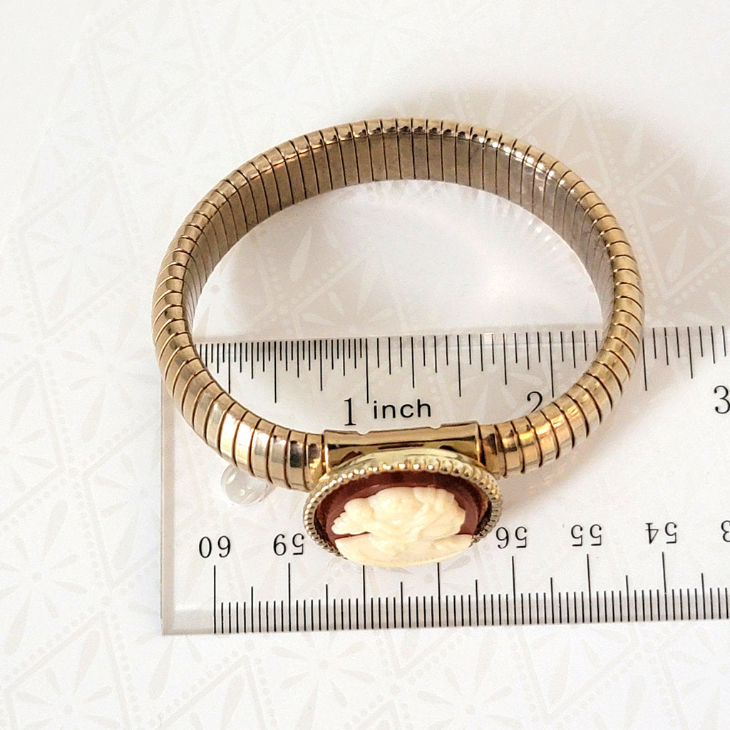 Vintage cameo, omega stretch bracelet, next to a ruler.