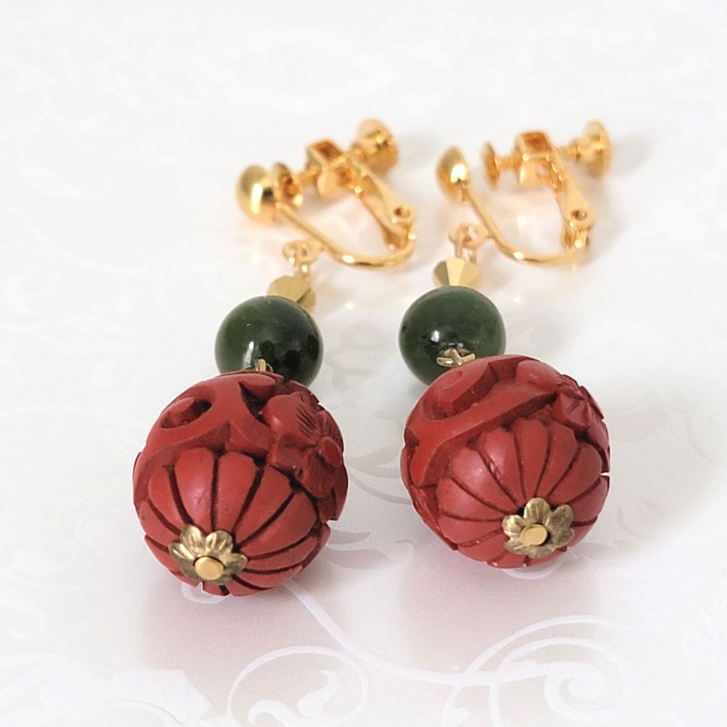 Bottom view of cinnabar style beaded clip earrings, with green stone accents.