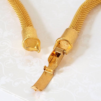 Closeup view of an open, gold tone, Anne Klein mesh necklace clasp.