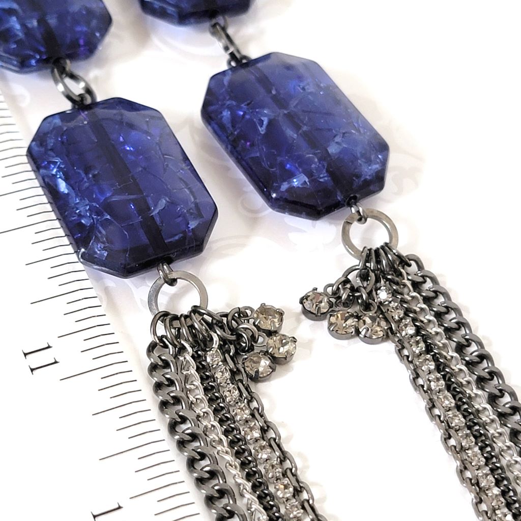Closeup view of a Kenneth Cole necklace, showing blue beads, gunmetal chains and rhinestones.