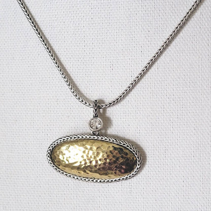 Premier Designs oval pendant choker in hammered gold and silver tone, with foxtail chain and crystal accent. Shown closeup, on a display stand.