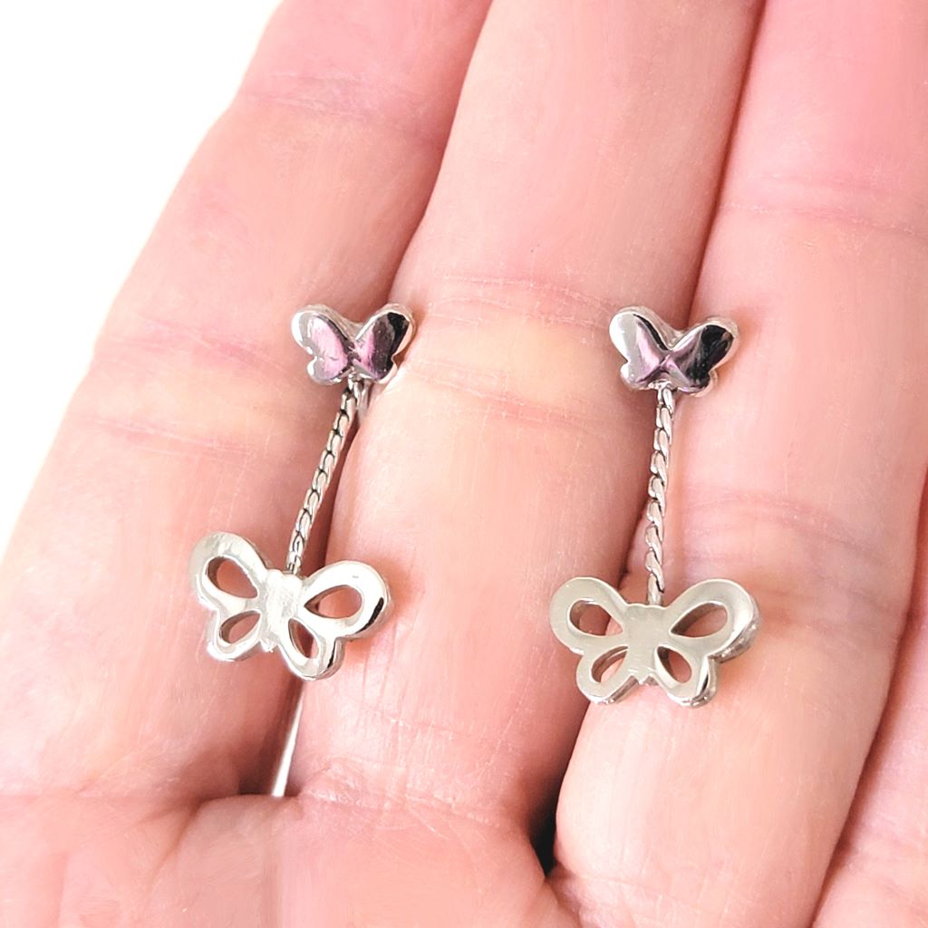 Crown Trifari butterfly dangle earrings, shown in hand.