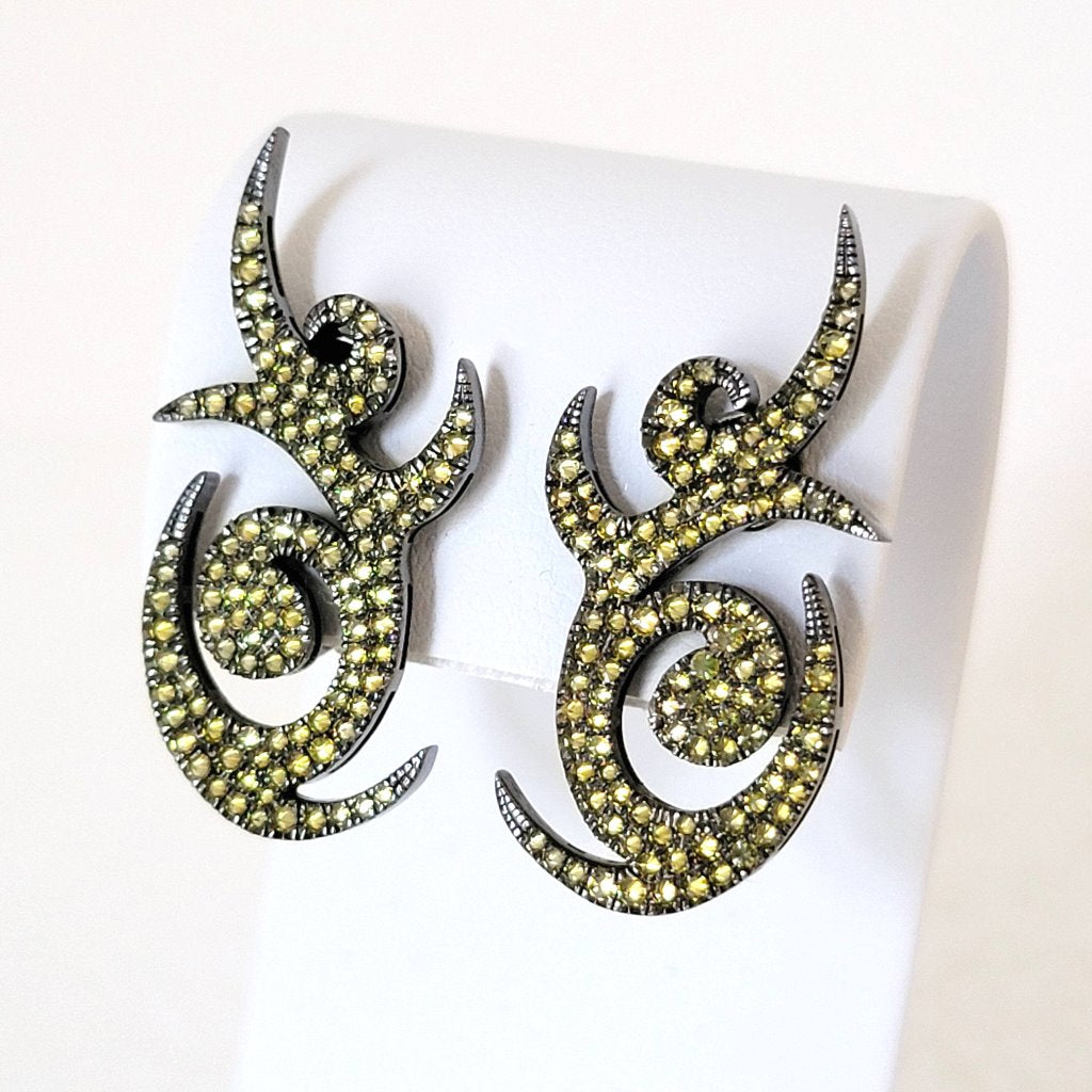 Curvy spikes yellow pave rhinestone clip earrings, closeup view, shown on display stand.