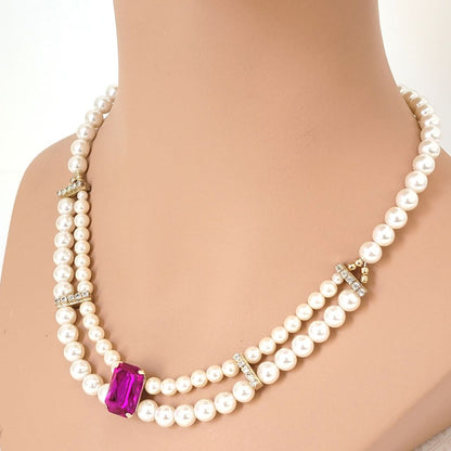 Faux pearl necklace with rhinestones and magenta pink acrylic focal, on a display bust.