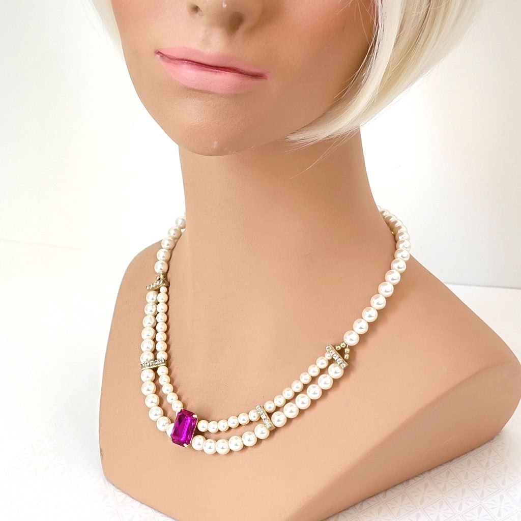 Vintage faux pearl necklace with rhinestones and magenta pink acrylic focal, displayed on a mannequin.