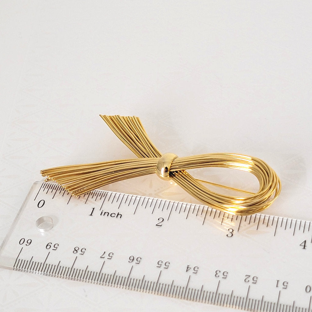 Vintage gold tone wire brooch, by Gantos, next to a ruler.