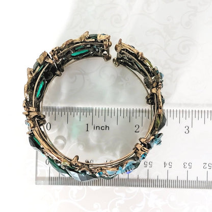 Emerald green rhinestone butterfly cuff bracelet, with blue flower accents. Shown next to a ruler.