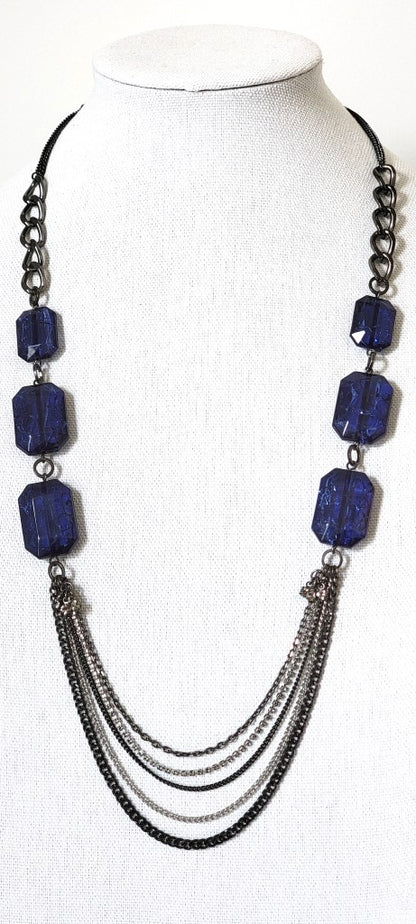 Kenneth Cole long blue bead and gunmetal chains necklace on a display stand.
