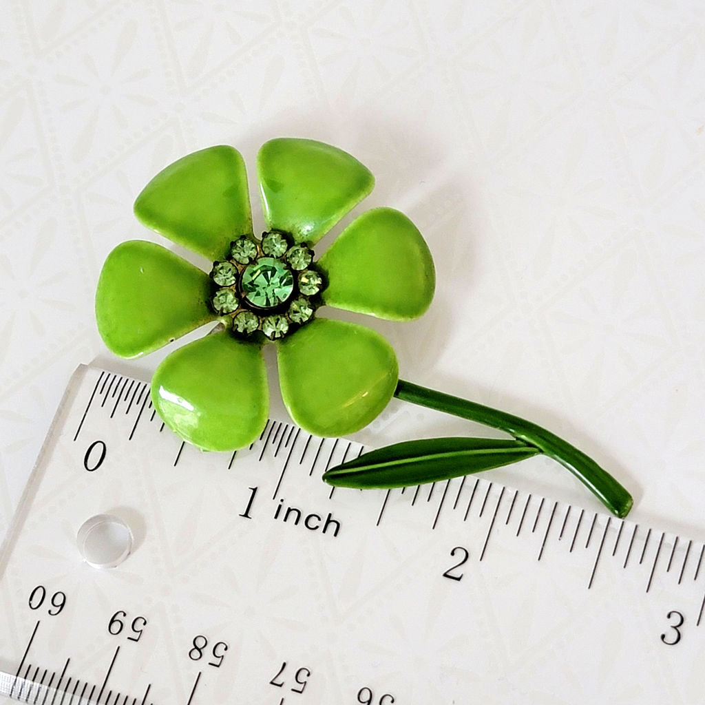 Vintage lime green enamel flower pin, next to a ruler.