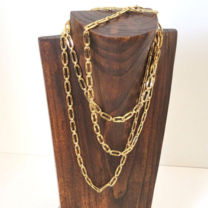 Long gold tone Monet chain necklace, triple wrapped, on a display stand.