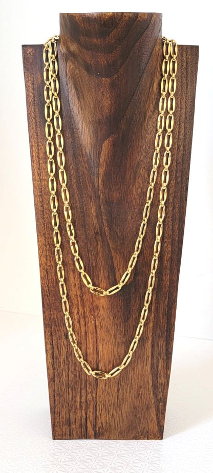 Long Monet gold tone chain, doubled, on a display stand.