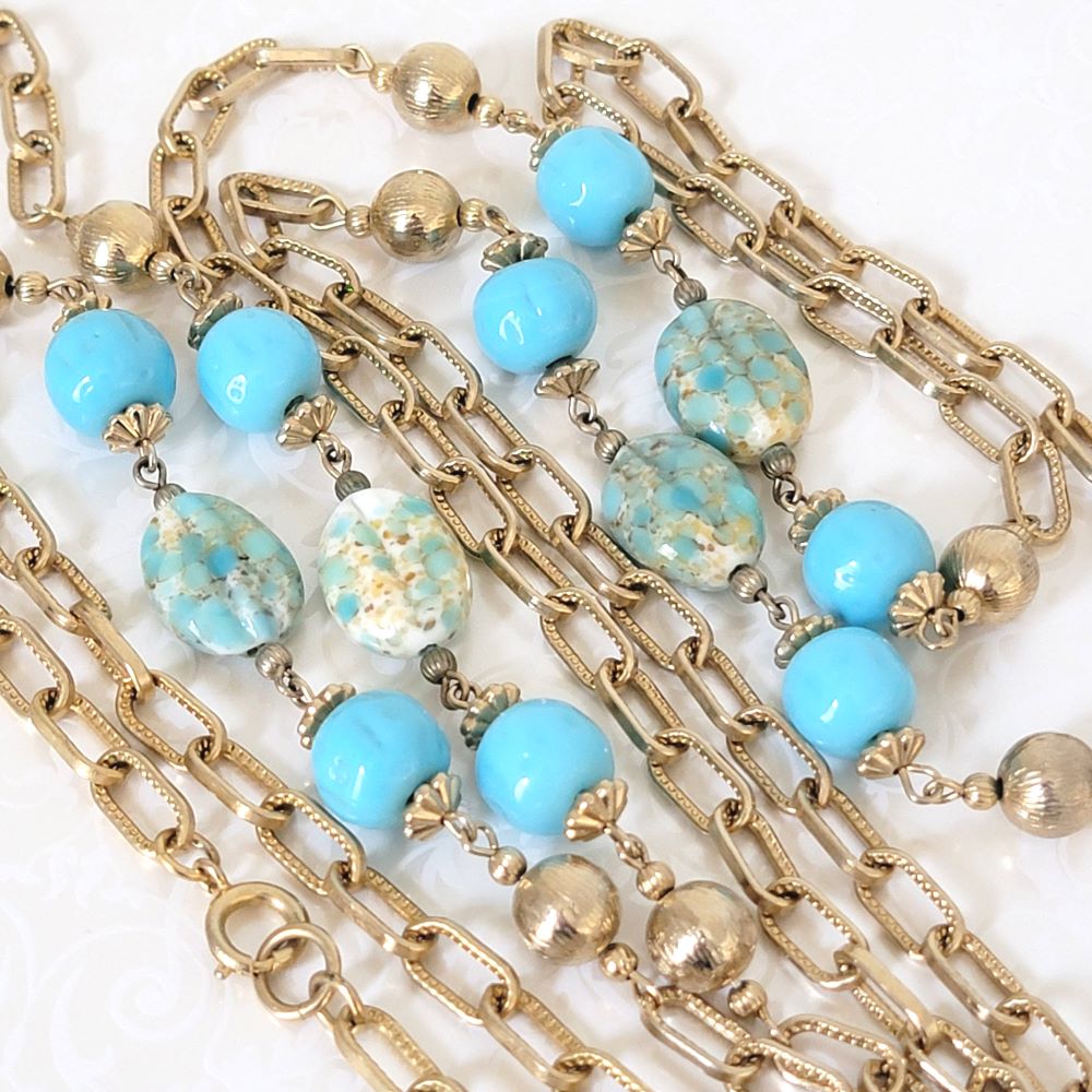Closeup view of vintage necklace with gold tone chain and robin's egg blue glass beads.