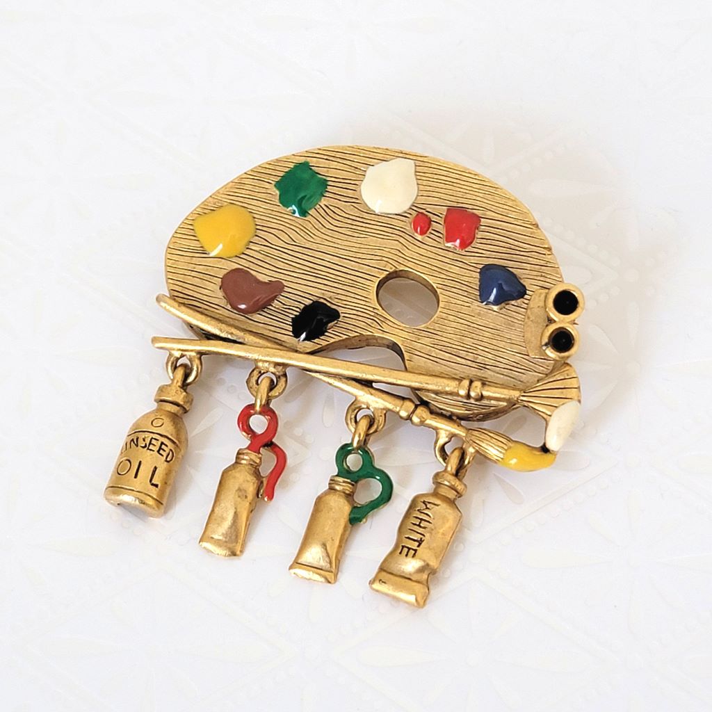 Danecraft painter's palette brooch, gold tone with multicolor enamel and dangling paint tubes.