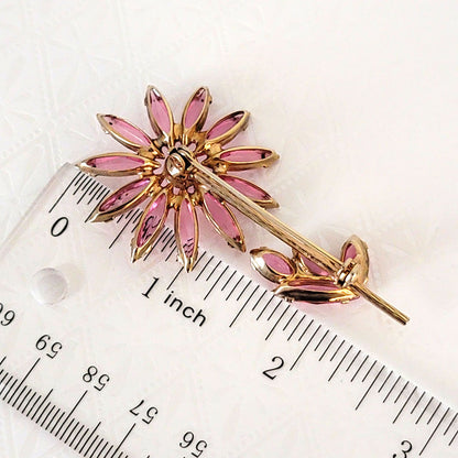 pink rhinestone flower pin next to a ruler