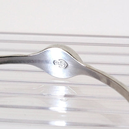 Inside view of a silver tone minimalist Premier Designs bracelet, showing signature mark.