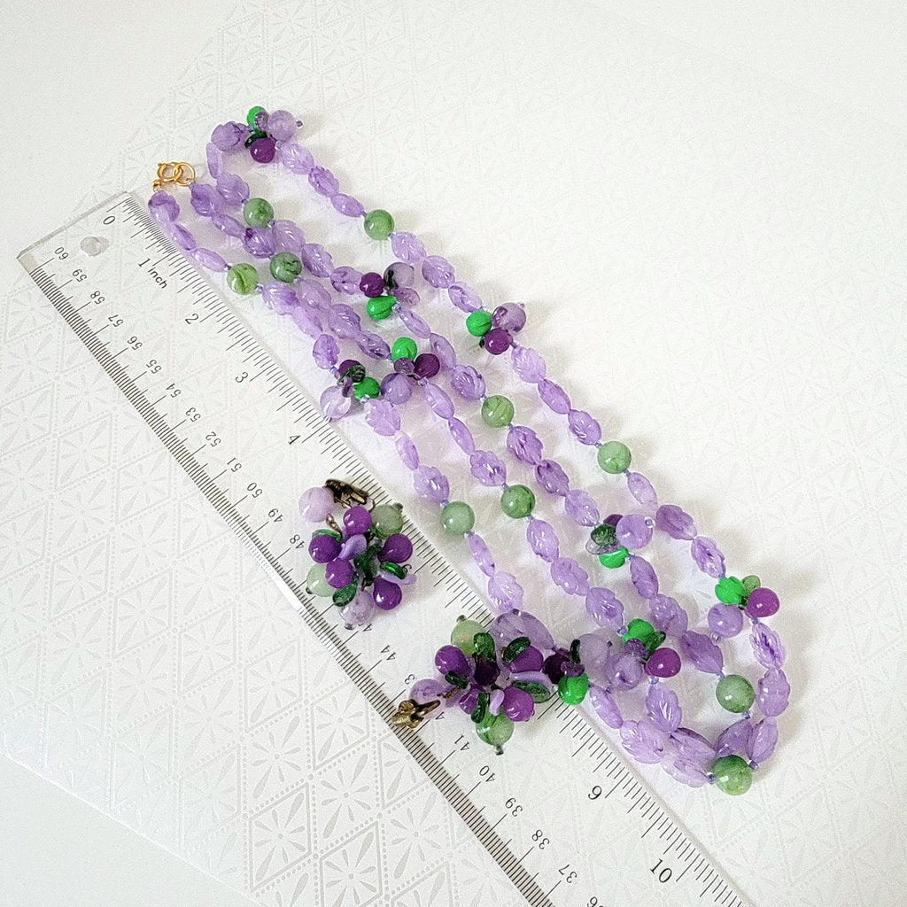 Purple lucite beaded necklace and earrings set, next to a ruler.