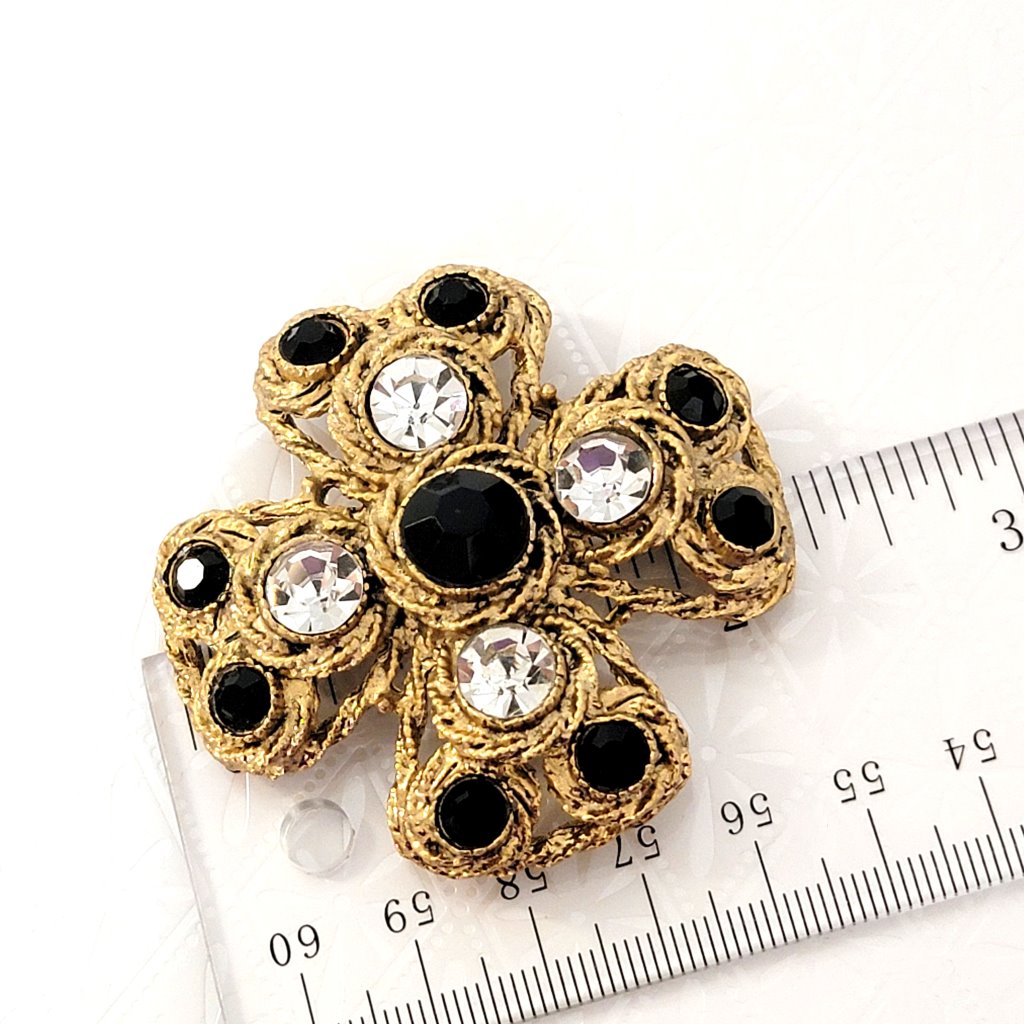 Large, textured gold tone Maltese cross rhinestone brooch, next to a ruler.