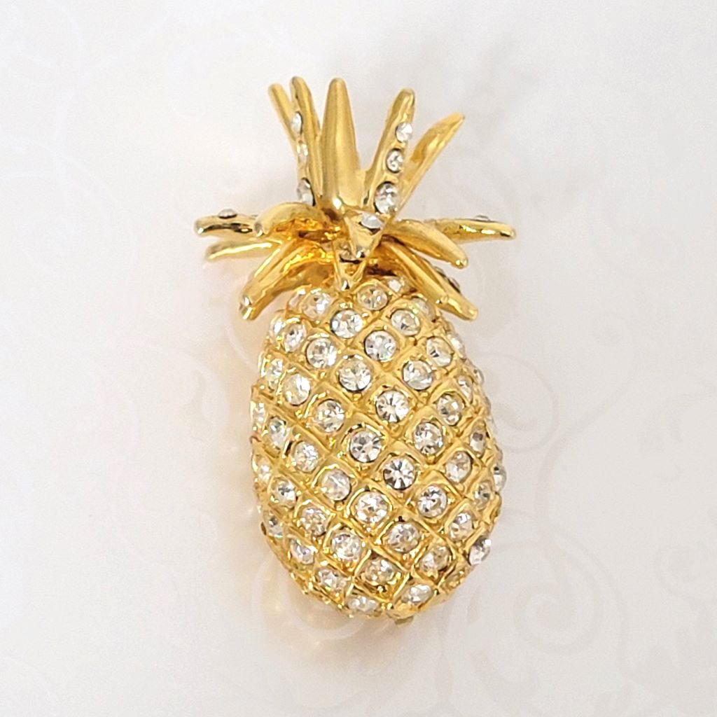 Pave style rhinestone pineapple brooch, in gold tone plating.