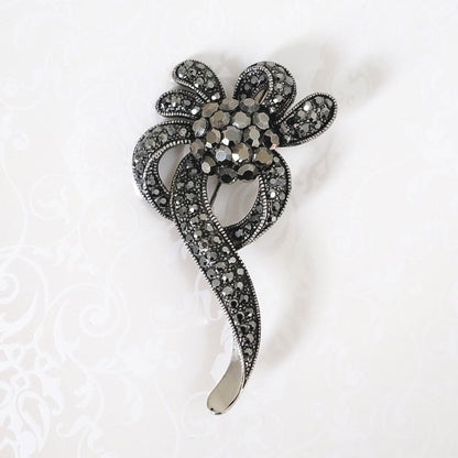 Silvery gray goth style rhinestone floral ribbon brooch, in antiqued silver tone setting.