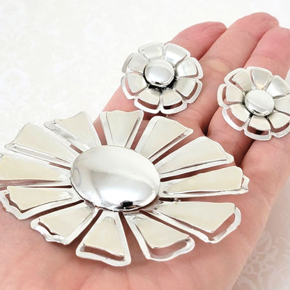Vintage silver tone 60s flower pin and earrings, shown in hand, for size comparison.