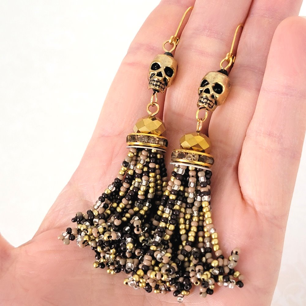 Skull dangle bead tassel earrings with rhinestones, shown in hand.