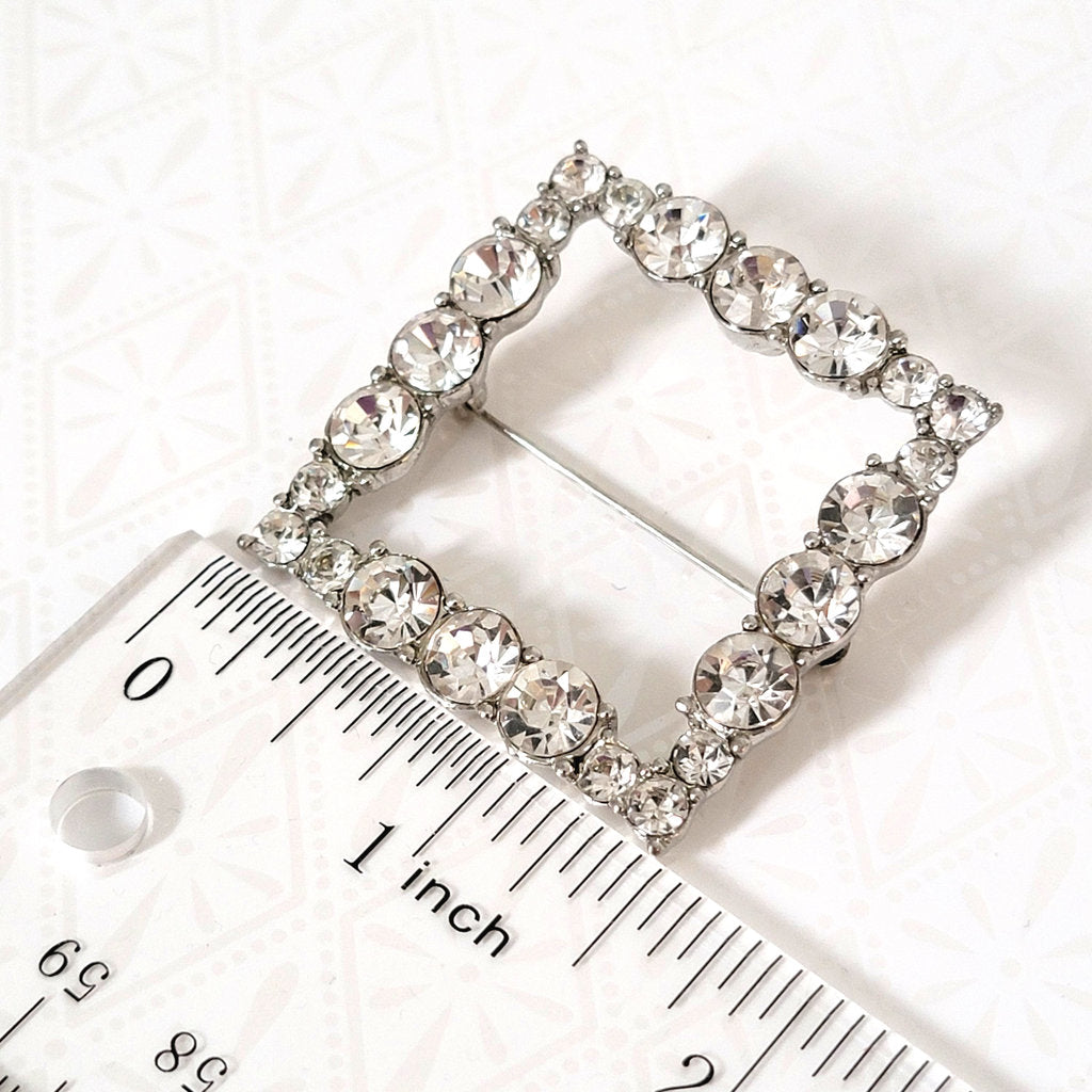 clear rhinestone square brooch next to a ruler